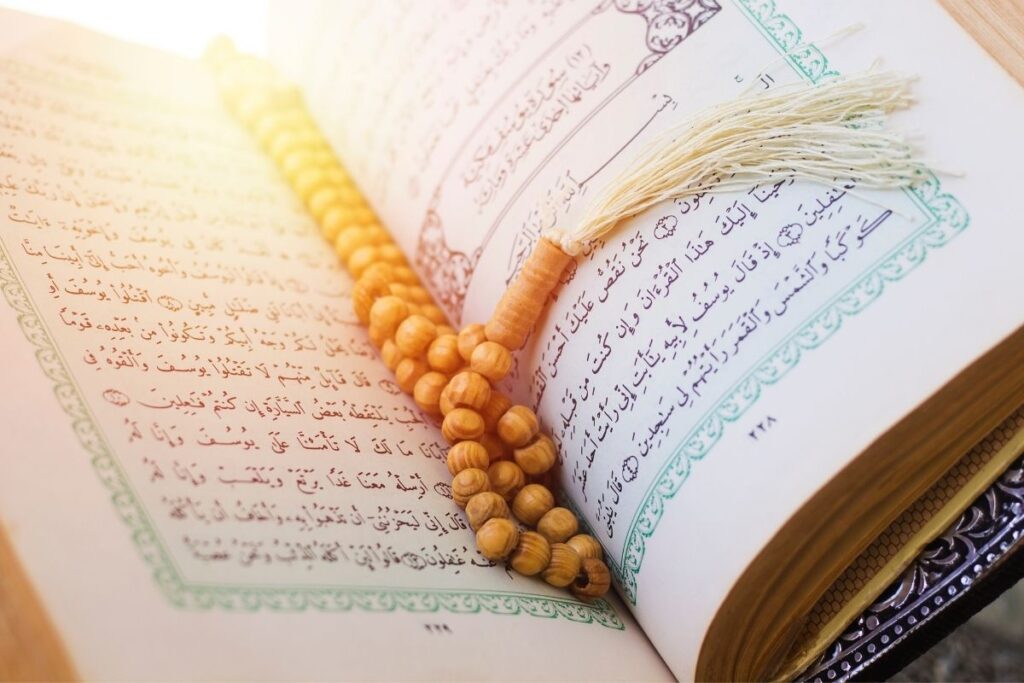 Open Quran with prayer beads under simple soft lighting